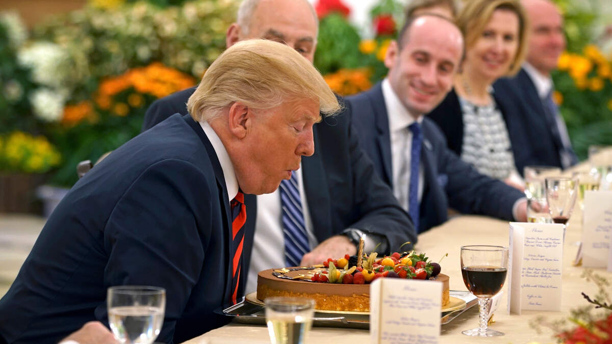 In this photo released by the Ministry of Communications and Information of Singapore, U.S. President Donald Trump blows out a candle on a cake celebrating an early birthday during lunch with Singapore's Prime Minister Lee Hsien Loong in Singapore, Monday, June 11, 2018. Trump turns 72 on Thursday.