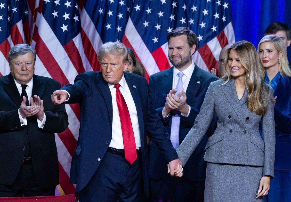 Donald Trump holds hands with wife Melania Trump at his Election Night Watch Party at the Palm Beach County Convention Center after being elected the 47th President of the United States. Viktor Knavs, JD Vance and Ivanka Trump also are in the photo.