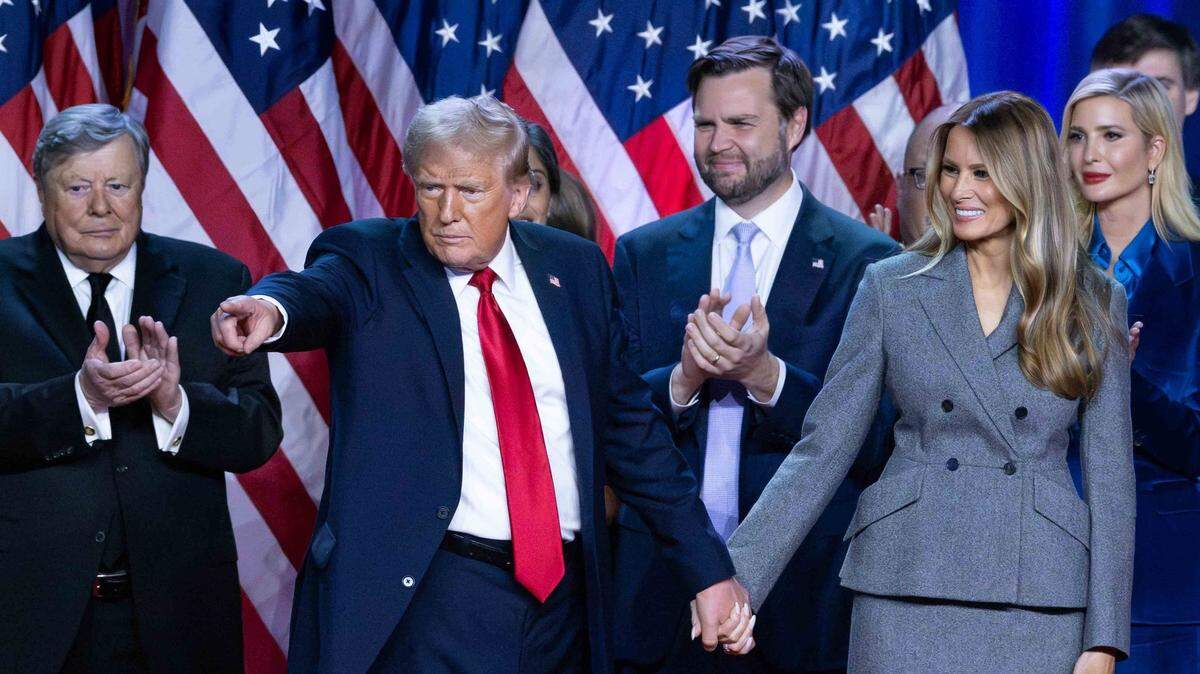 Donald Trump holds hands with wife Melania Trump at his Election Night Watch Party at the Palm Beach County Convention Center after being elected the 47th President of the United States. Viktor Knavs, JD Vance and Ivanka Trump also are in the photo.