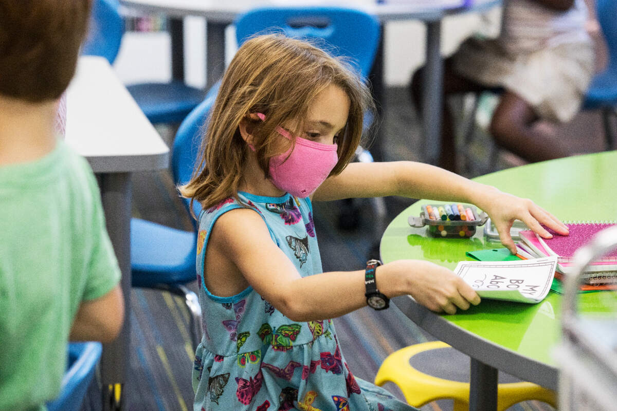 A first-grade student at Conn Elementary School in Raleigh, N.C. prepares her desk for the first day of school, Monday, Aug. 23, 2021.