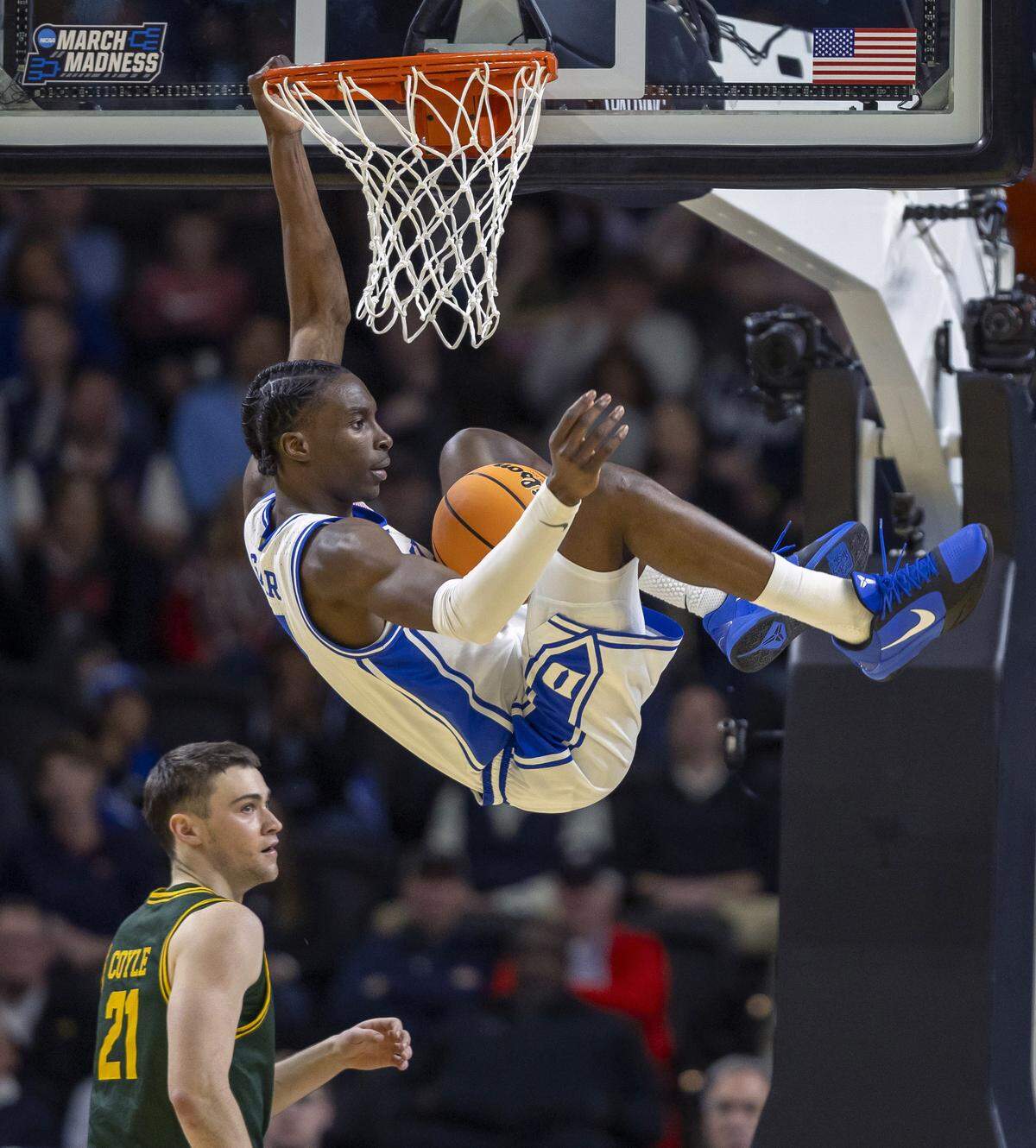 Duke guard Dame Sarr (7) hangs on the rim after a dunk over Siena guard Brendan Coyle (21) to pull the Blue Devils to within two points in the second half on Thursday, March 18, 2026, during the first round of the NCAA Tournament at Bon Secours Arena in Greenville, S.C.