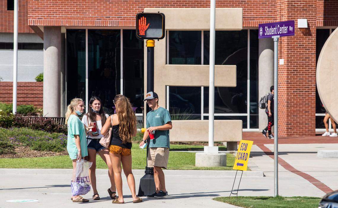 Students, not wearing masks, wait to cross 10th street Tuesday, August 18, 2020 outside the Student Center at East Carolina University.