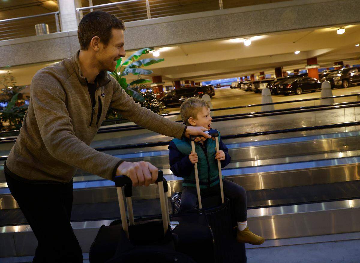 Aaron Sharp pushes his son, Charlie, 4, atop a rolling suitcase in a parking garage at Raleigh-Durham International Airport on Thursday, Dec. 22, 2022. The father and son were headed to visit family in Nashville following a flight delay.