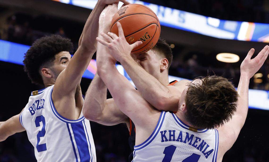 Virginia's Dallin Hall (30) is fouled by Duke’s Nikolas Khamenia (14) as Cayden Boozer (2) also defends during the first half of Duke’s game against Virginia in the finals of the 2026 ACC Men’s Basketball Tournament at the Spectrum Center in Charlotte, N.C., Saturday, March 14, 2026.