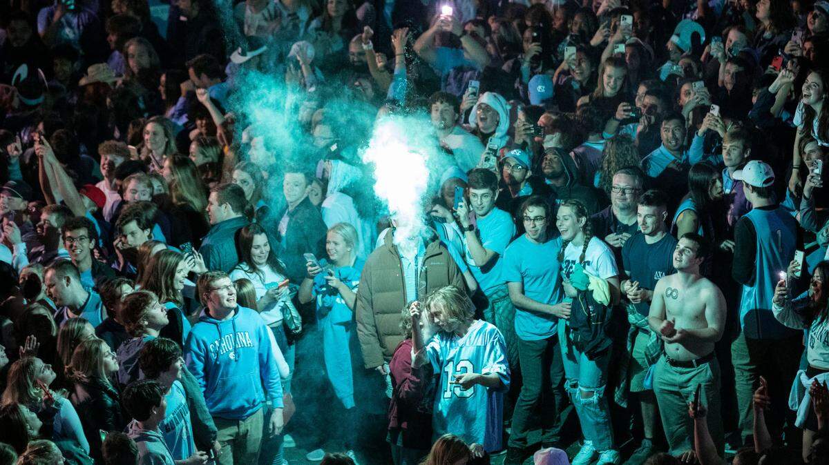 A Tar Heel fan launches a firework that lights up a celebrating crowd at the intersection of Franklin and Columbia Streets in Chapel Hill, N.C. after a historic win against Duke in the Final Four on Saturday, April 2, 2022.
