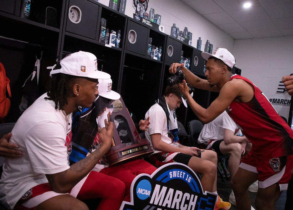 N.C. State’s KJ Keatts takes a photo of the NCAA Tournament South Regional Champion trophy in the locker room following the Wolfpack’s 76-64 win over Duke on Sunday, March 31, 2024, at American Airlines Center in Dallas, Texas.