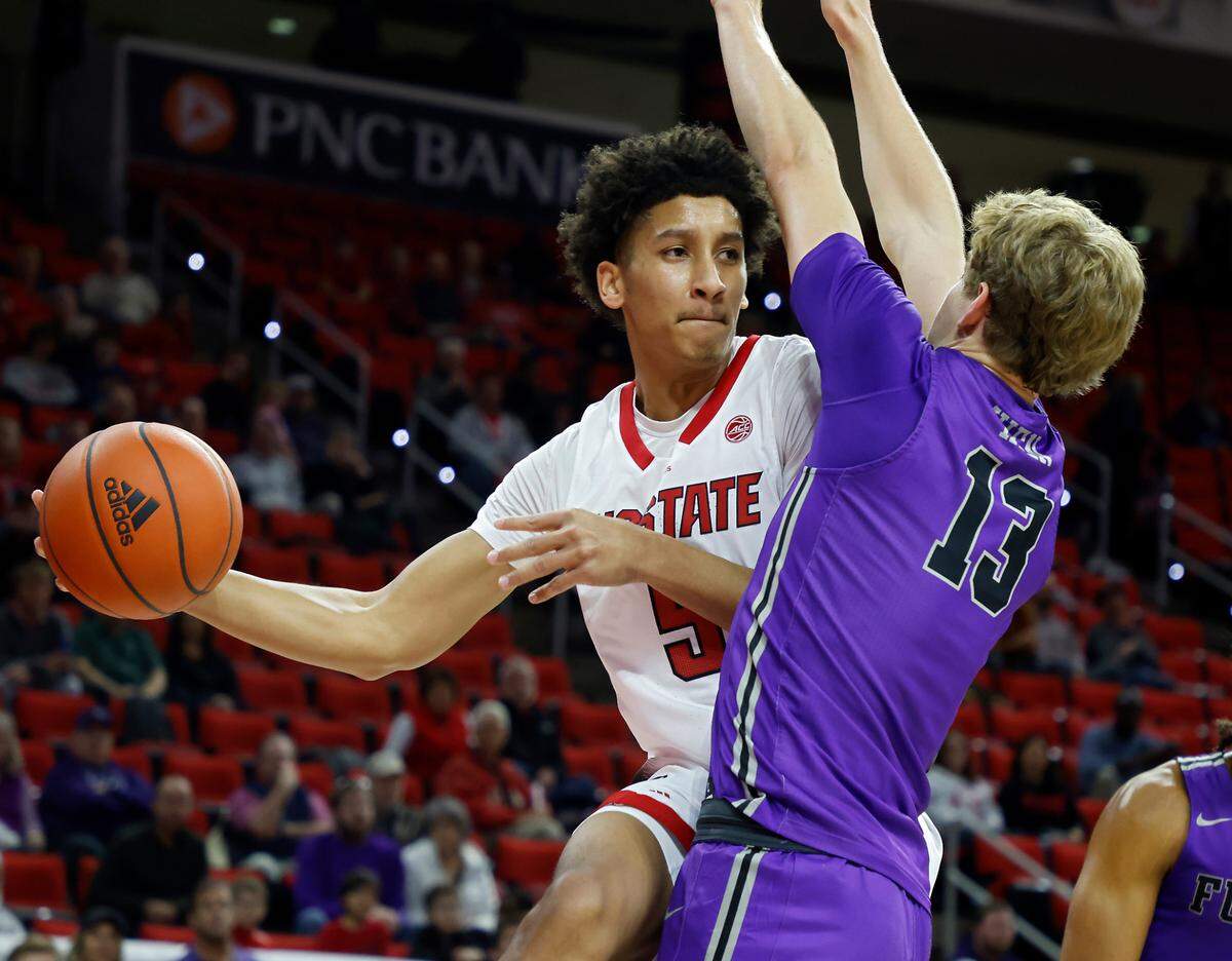 North Carolina State’s Jack Clark looks to pass around Furman’s Garrett Hien during the first half of a men’s basketball game at PNC Arena on Tuesday, Dec. 13, 2022, in Raleigh, N.C.