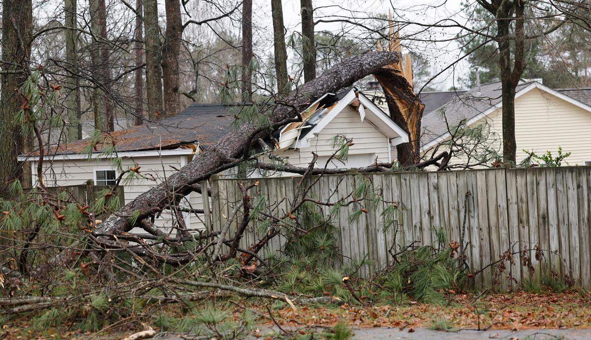 A snapped tree sits on top of a garage as seen from Woodland Road in Garner, N.C., Sunday, Dec. 10, 2023. A powerful storm roared through the area, knocking down trees and cutting off power.