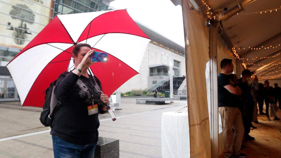 IMBA volunteer Paige McKinstry of Durham, NC used her break to wander and use her smartphone with the aid of her umbrella to make a personal video of the Cane Creek Cloggers performing in the South Salisbury Street Dance Tent Friday afternoon, October 2, 2015 during the 2015 Wide Open Bluegrass Festival at the Raleigh Convention Center. The weekend’s rain and wind moved most of the outdoor venues inside, but the dance tent show still went on Friday.