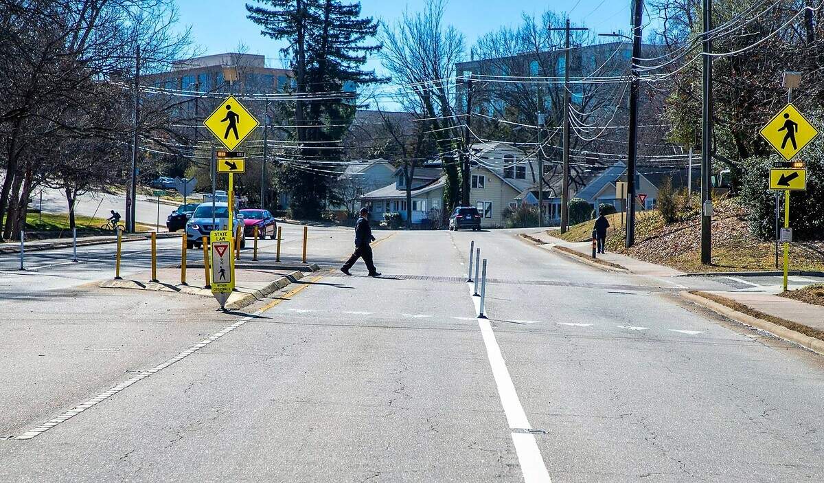 A pedestrian uses the marked crosswalk to get across Martin Luther King Jr. Boulevard in front of Chapel Hill’s Town Hall building. The town recently installed bollards at the crosswalk to slow down traffic and prevent cars from switching lanes to pass pedestrians.