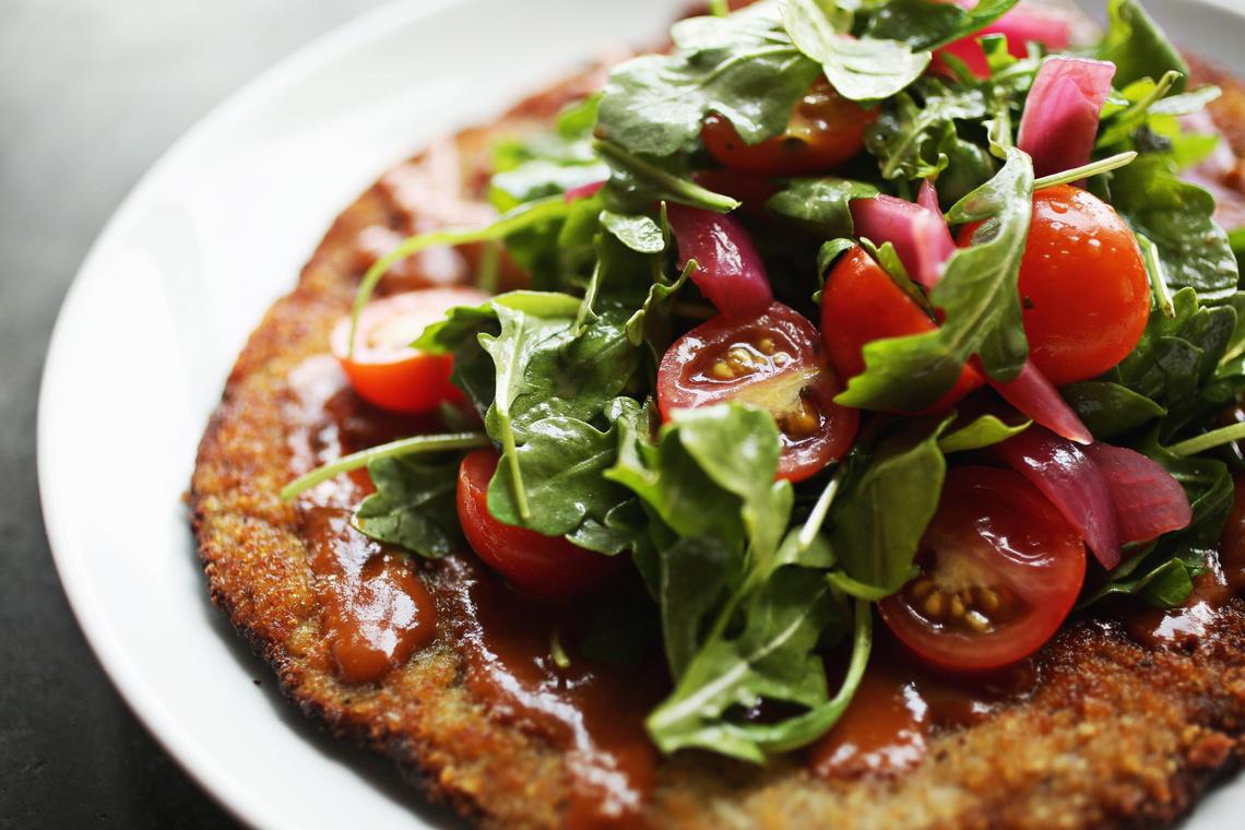 The tonkatsu milanese is made up of a boneless heritage pork chop, topped with a tomato katsu sauce and a small salad of arugula and pickled red onion in a yuzu vinaigrette at Papa Shogun in Raleigh.