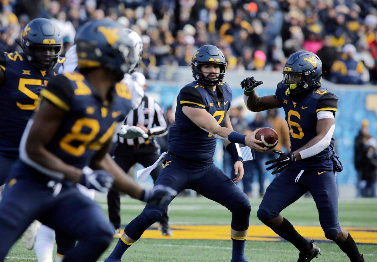 West Virginia quarterback Will Grier (7) hands the ball off to running back Kennedy McKoy (6) during the first half of an NCAA college football game against TCU, Saturday, Nov. 10, 2018, in Morgantown, W.Va.