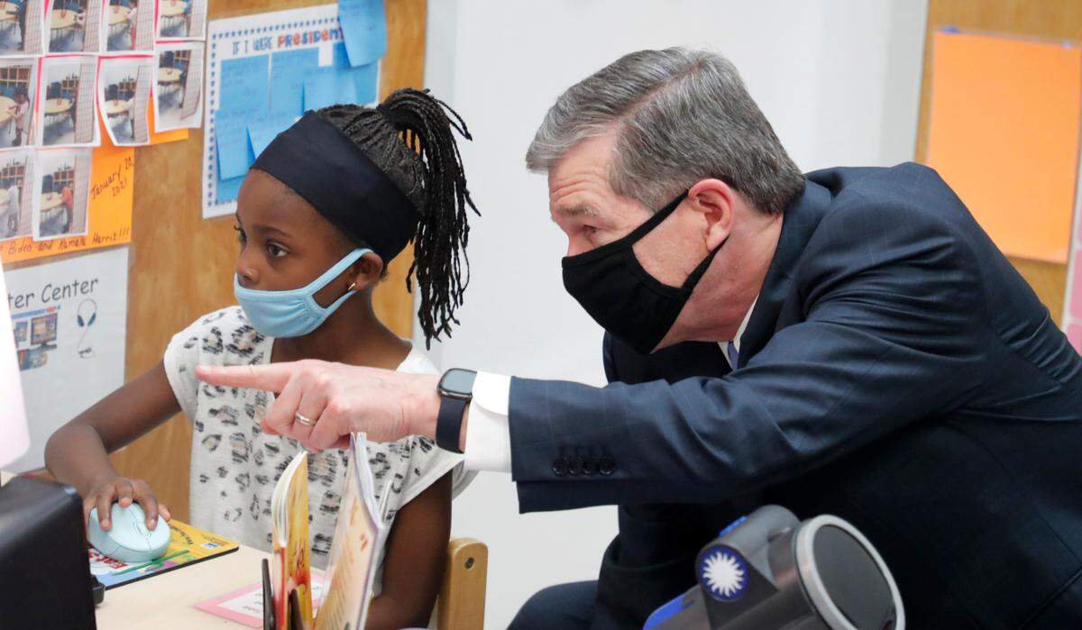 N.C. Gov. Roy Cooper talks with Mia Tong during a tour by Gov. Cooper and U.S. Education Secretary Miguel Cardona at Bright Beginnings Child Development Center in Cary, N.C., Thursday, May 20, 2021.