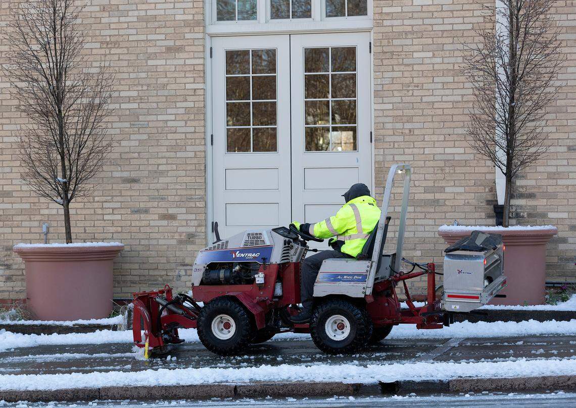 A person works to clear snow and ice from a sidewalk along Foster Street in downtown Durham, N.C. on Saturday, Jan. 11, 2025.
