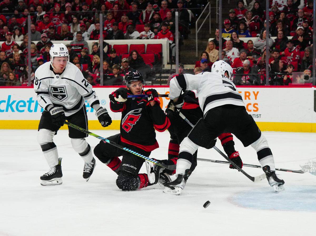 Jan 15, 2024; Raleigh, North Carolina, USA; Los Angeles Kings defenseman Matt Roy (3) and center Jaret Anderson-Dolan (28) check Carolina Hurricanes center Jesperi Kotkaniemi (82) off the puck during the first period at PNC Arena.