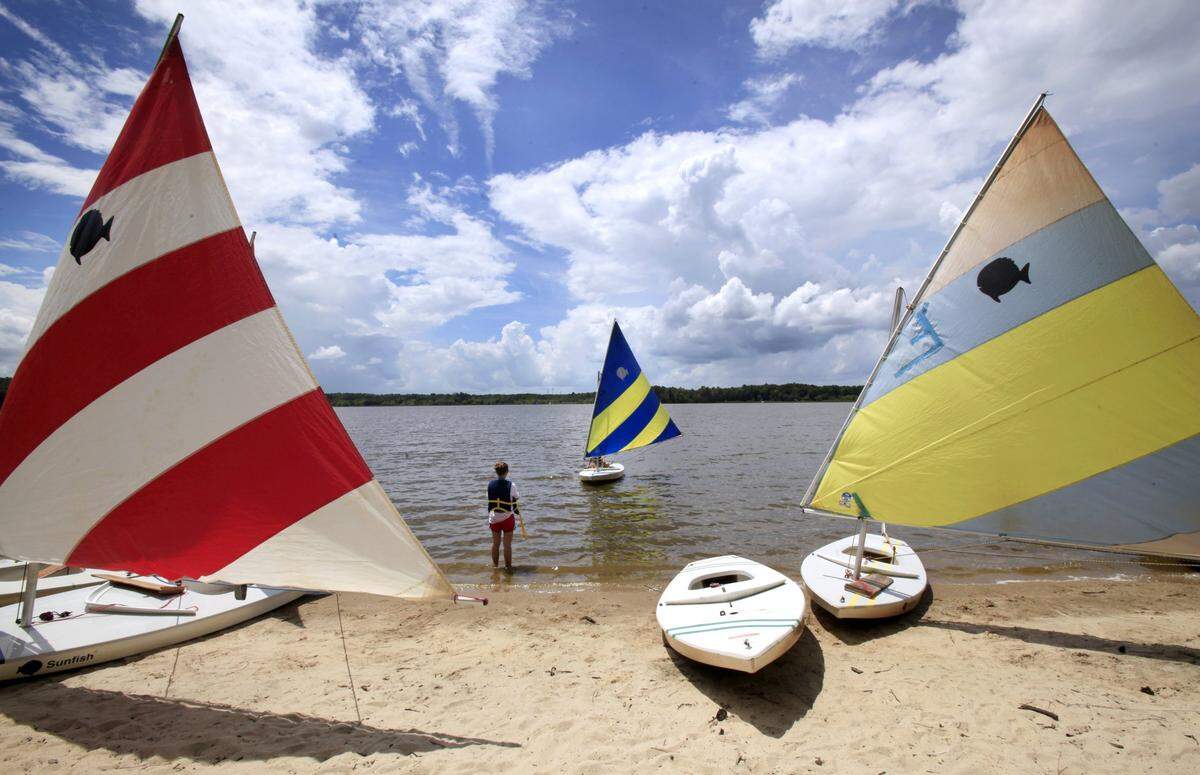 Aleta Donald, 13, of Chapel Hill, watches the sailboat operated by her mother, Jennifer Groh, appoach to the shore of Lake Crabtree in an August 2012 file photo. On weekends, a dozen sailboats, along with kayaks, canoes and pedal boats, are available for rent at Lake Crabtree Park.