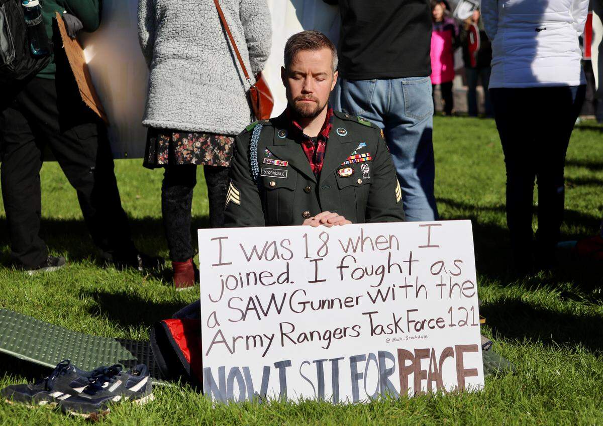 Veteran Zach Stockdale sits in quiet next to the crowd of protesters during anti-war protests in Raleigh, N.C. on January 5, 2020. Stockdale continued sitting through all of the speeches.