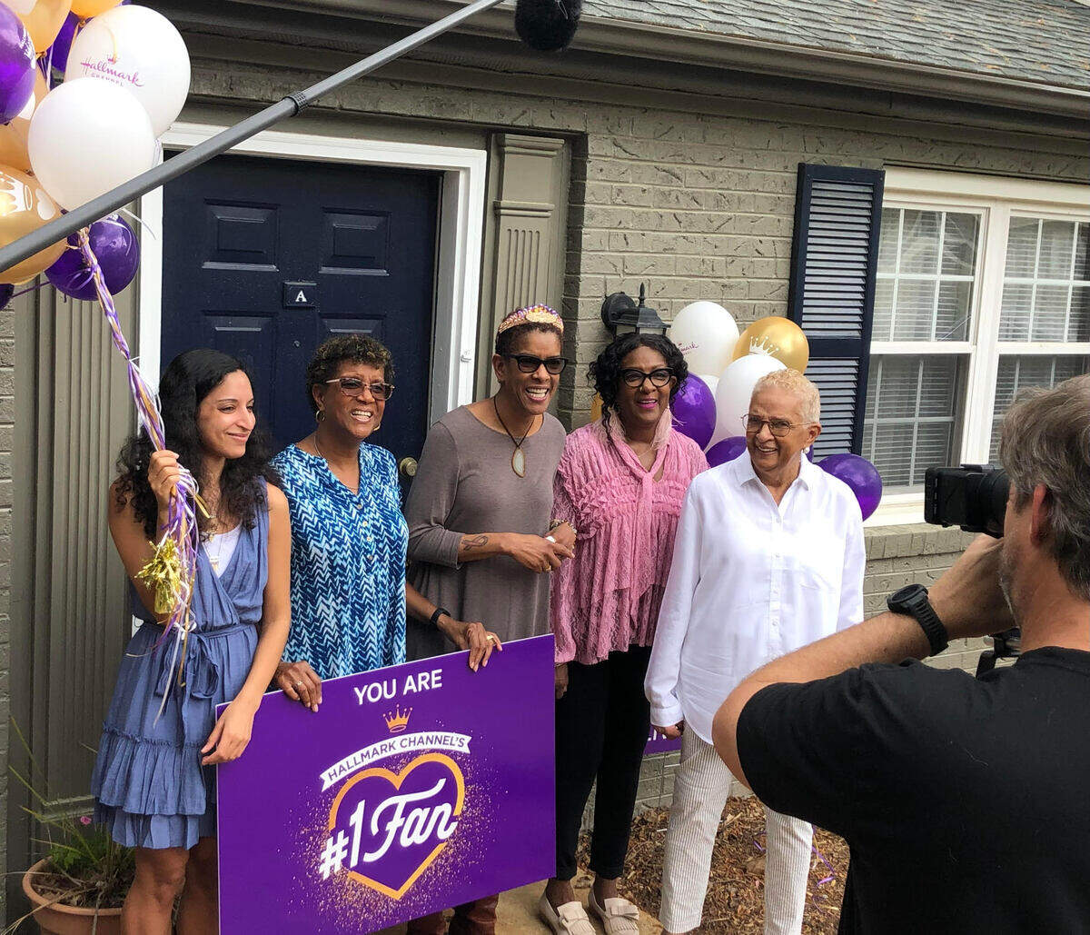 Taborah Adams of Cary, center, with her sisters, mother and niece, face the Hallmark Channel’s cameras Thursday after Adams was named winner of the network’s No. 1 fan contest.