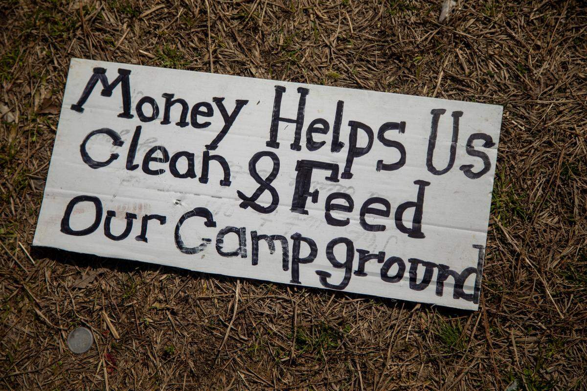 A sign lays on the ground near a camp between Interstate 540 and an exit ramp to Capital Boulevard that is littered with trash and debris. The NCDOT has received numerous complaints about the site.