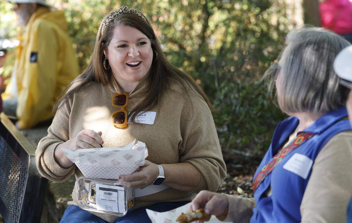 Laura Robinson laughs with her mom and sister while eating food from Lawrence & Perry BBQ during the Foodie's Tour of the State Fair at the N.C. State Fair in Raleigh, N.C., Friday, October 17, 2025.