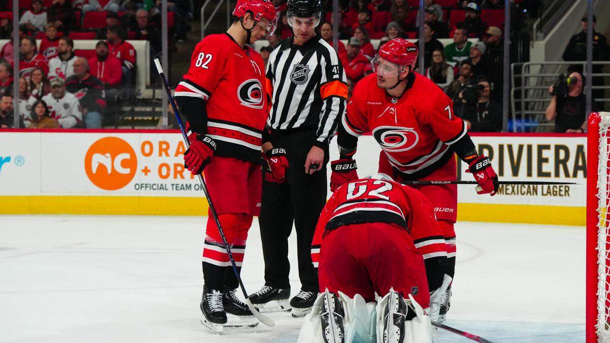 Jan 11, 2024; Raleigh, North Carolina, USA; Carolina Hurricanes goaltender Pyotr Kochetkov (52) kneels on the ice next to defenseman Dmitry Orlov (7) and center Jesperi Kotkaniemi (82) with referee Cody Beach (45) against the Anaheim Ducks during the second period at PNC Arena. Mandatory Credit: James Guillory-USA TODAY Sports