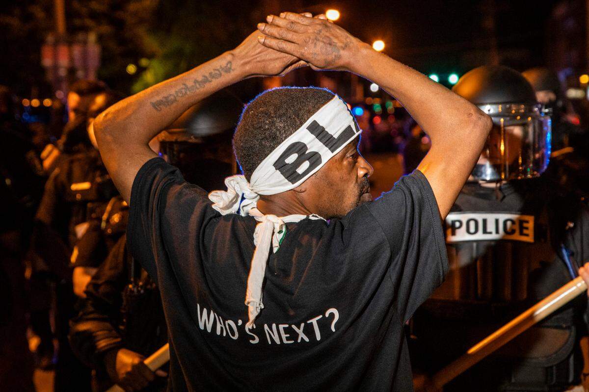 A demonstrator protesting the police killing of Andrew Brown Jr. raises their hands in front of a police line Tuesday, April 27, 2021 in downtown Elizabeth City . At least six protesters were arrested when police in riot gear marched toward roughly a dozen protesters two hours past curfew. Protesters were peaceful but refused to clear the streets.