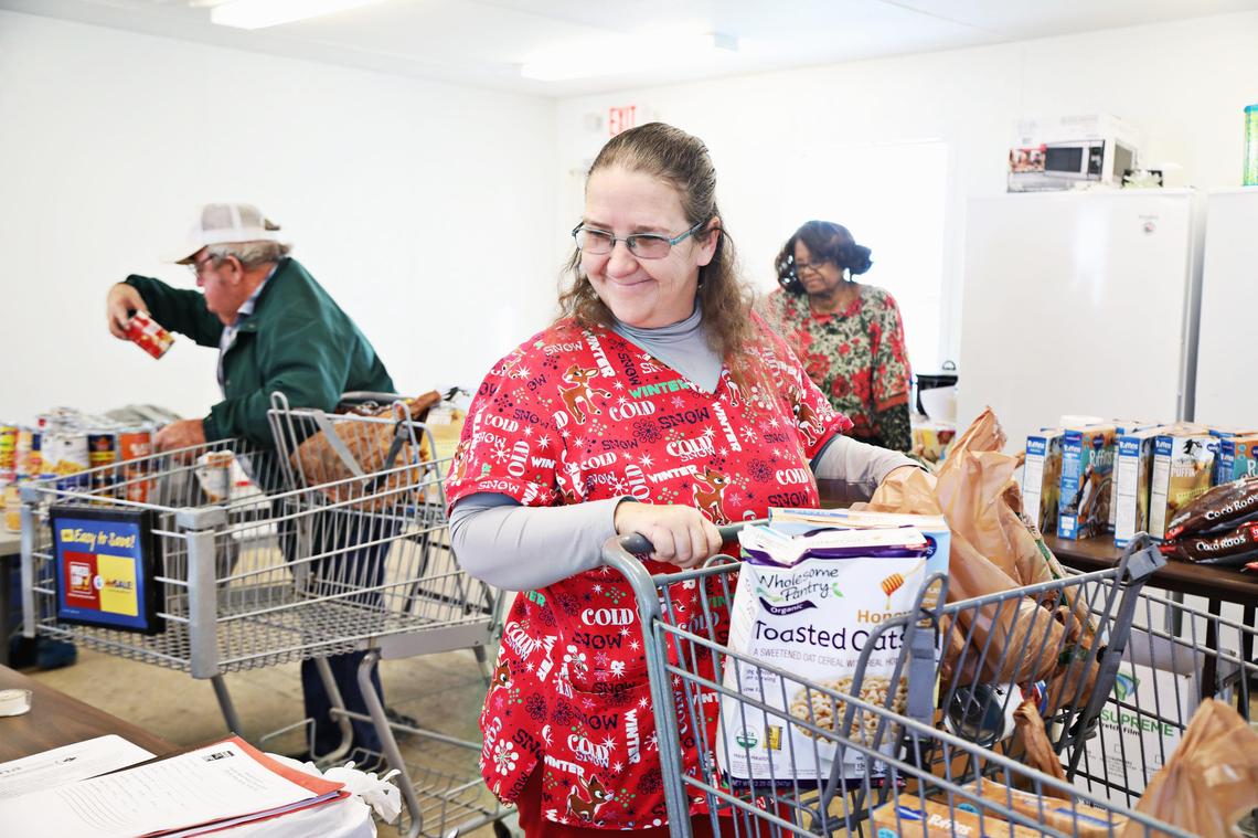 Clients Haywood Jones, left, Becky Blevins, center, pick up groceries at the Disaster Recovery Food Pantry in Trenton, Tuesday morning, Nov. 26, 2019.
