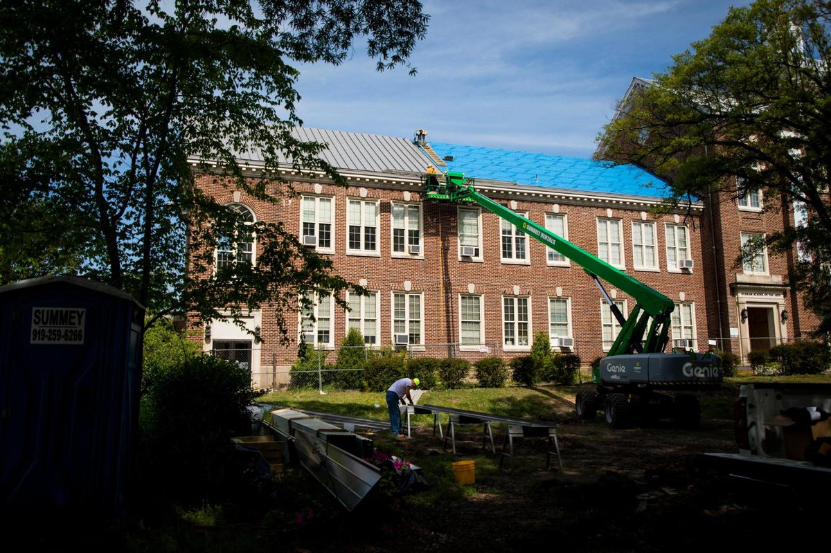 A roofing crew installs a new metal roof on the Durham School of the Arts in Durham on April 20, 2021.