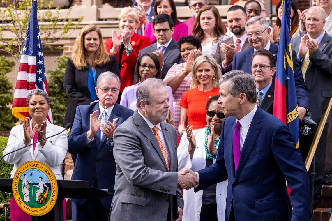 Gov. Roy Cooper, left, shakes hands with Senate Leader Phil Berger before signing a Medicaid expansion bill into law during a ceremony at the Executive Mansion Monday, March 27, 2023.