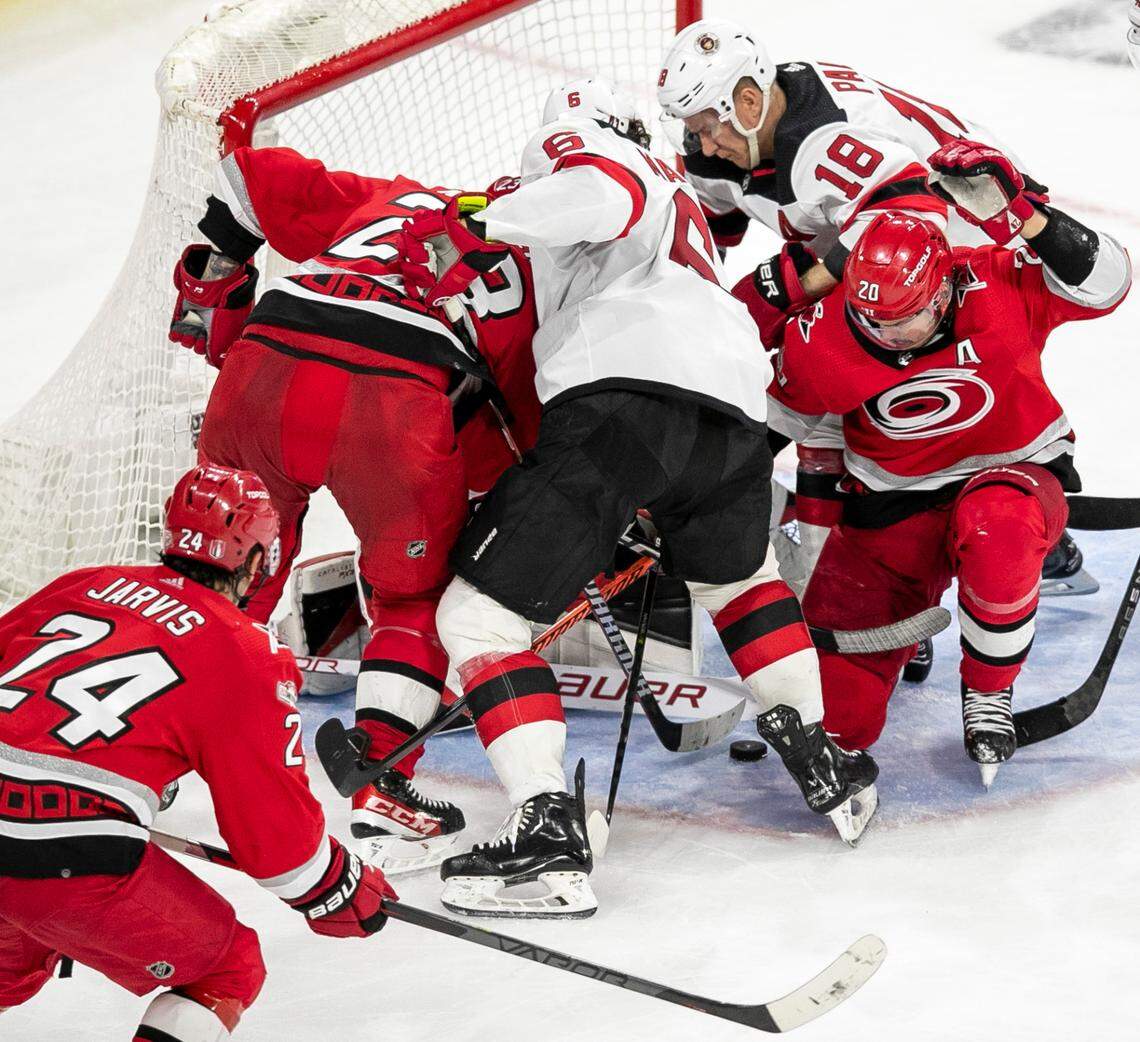 The Carolina Hurricanes Stefan Noesen (23) and Sebastian Aho (20) try to get their sticks on the puck in the crease against New Jersey Devils goalie Akira Schmid (40) in the third period during Game 5 of their second round Stanley Cup playoff series on Thursday, May 11, 2023 at PNC Arena in Raleigh, N.C.