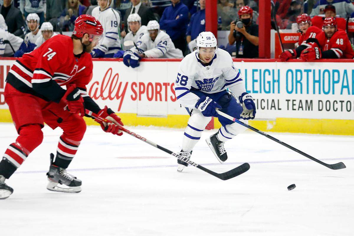 Toronto Maple Leafs’ Michael Bunting (58) battles with Carolina Hurricanes’ Jaccob Slavin (74) for the puck during the first period of an NHL hockey game in Raleigh, N.C., Monday, Oct. 25, 2021. (AP Photo/Karl B DeBlaker)
