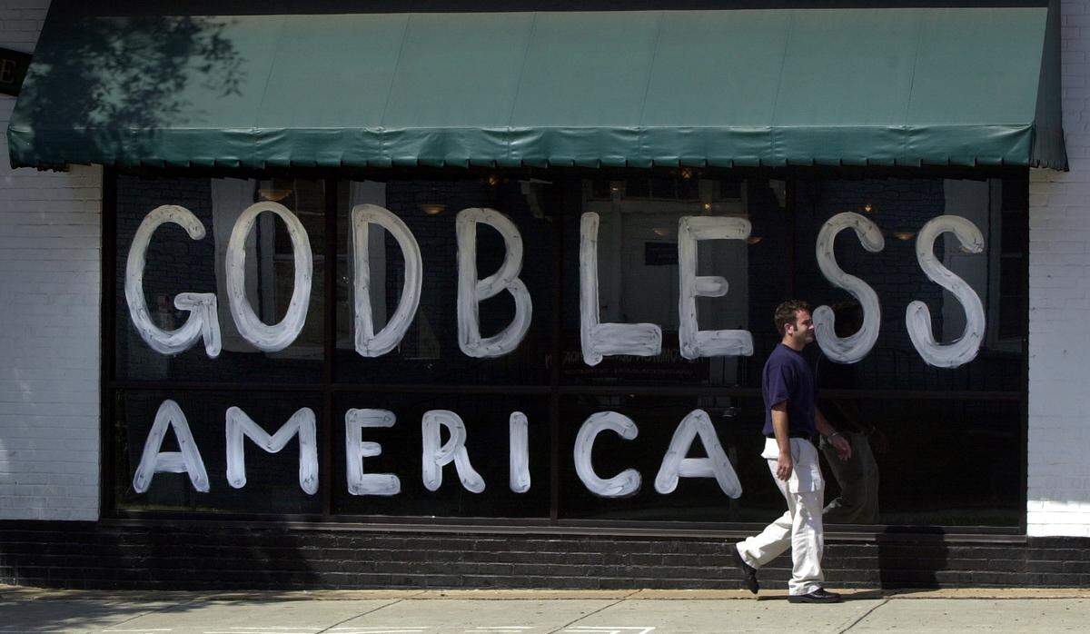Kyle Marsh walks by a window at the Flying Saucer at the corner of Harrington and Morgan Streets. The windows were with the patriotic “GOD BLESS AMERICA” was painted by employees at the brew emporium Tuesday night following terrorist attacks in New York and Washington, D.C.