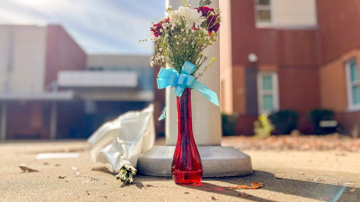 Flowers sit it at the base of a flagpole at Southeast Raleigh High School Tuesday morning, Nov 28, 2023. A 14-year-old has been charged with fatally stabbing a student and injuring another during a fight at the school on Monday morning.