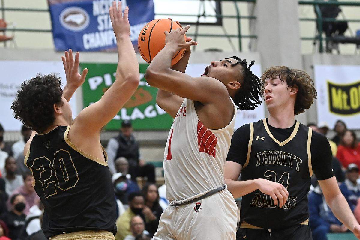 Trinity Academy’s Trey Barker (20) and Sam Perez (24) defend The Burlington School’s Zion Walker (1) in the first half. The Burlington School Spartans and the Trinity Academy Tigers met in the NCISAA 2A boys Final in Mt. Olive, N.C. on February 26, 2022. The Burlington School wins 57-45.