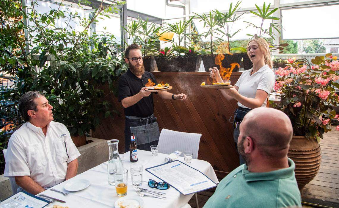Food runner Lee Baine and server Charlotte Jones bring saganaki flaming cheese dishes to diners Wednesday, June 16, 2021 at Taverna Agora Greek Kitchen & Bar in Raleigh. Many restaurants say business is starting to return to normal as coronavirus restrictions have lifted but hiring remains a challenge.