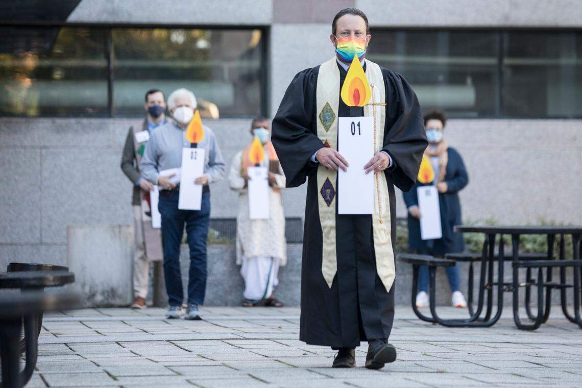 Rev. Sean Allen carries a candle poster representing the year 2001, one of the 28 years that have passed since the start of the Leandro court case in 1994, during a prayer vigil held by Pastors for NC Children in Bicentennial Plaza in Raleigh, N.C. on Monday, Oct. 18, 2021.