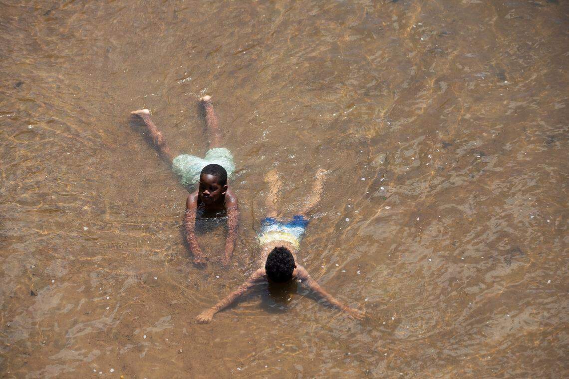Bryson Lewis, 7, and Cayson Hernandez, 6, cool off in the Neuse River on Thursday, June 20, 2024, in Durham, N.C.