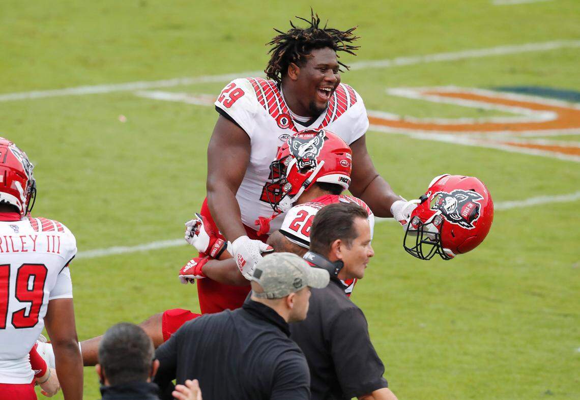 N.C. State defensive tackle Alim McNeill (29) celebrates with running back Trent Pennix (26) after Pennix scored on a five-yard touchdown reception during the first half of N.C. State’s game against Virginia at Scott Stadium in Charlottesville, Va., Saturday, Oct. 10, 2020.
