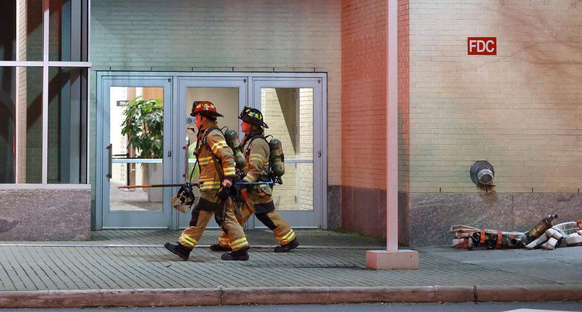 Firefighters walk past an entrance to the Raleigh Convention Center while battling a blaze at the center in downtown Raleigh, N.C., Monday evening, Dec. 1, 2025.