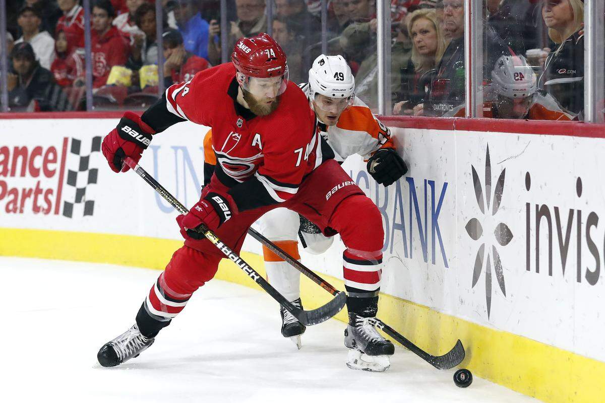 Carolina Hurricanes defenseman Jaccob Slavin (74) and Philadelphia Flyers left wing Joel Farabee (49) chase the puck during the first period of an NHL hockey game in Raleigh, N.C., Tuesday, Jan. 7, 2020.