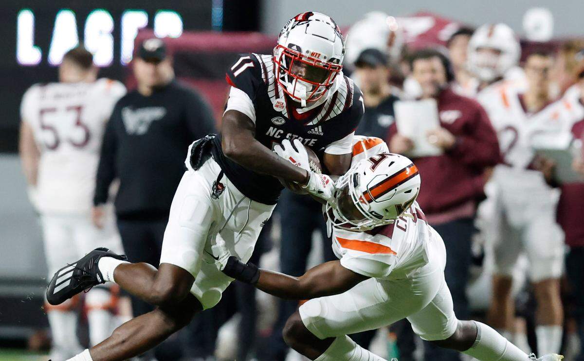 N.C. State wide receiver Darryl Jones (11) looks to gain yards after making a reception as Virginia Tech defensive back Armani Chatman (9) tries to tackle him during the first half of N.C. State’s game against Virginia Tech at Carter-Finley Stadium in Raleigh, N.C., Thursday, Oct. 27, 2022.