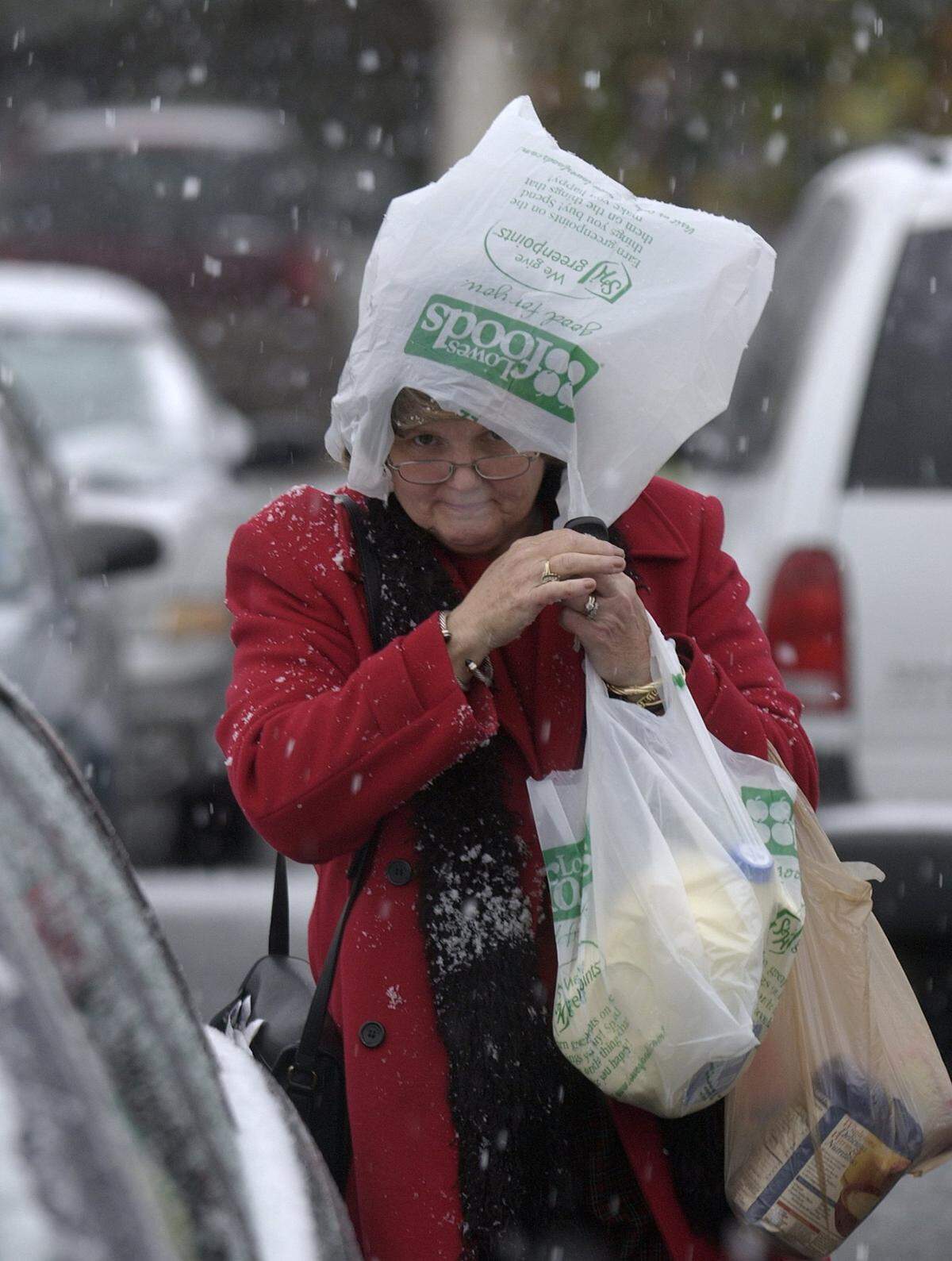 Joanne Smith looks up from her makeshift snow shelter of a plastic grocery bag as she makes her way to her car in the afternoon snow and ice Wednesday, Dec. 4, 2002.