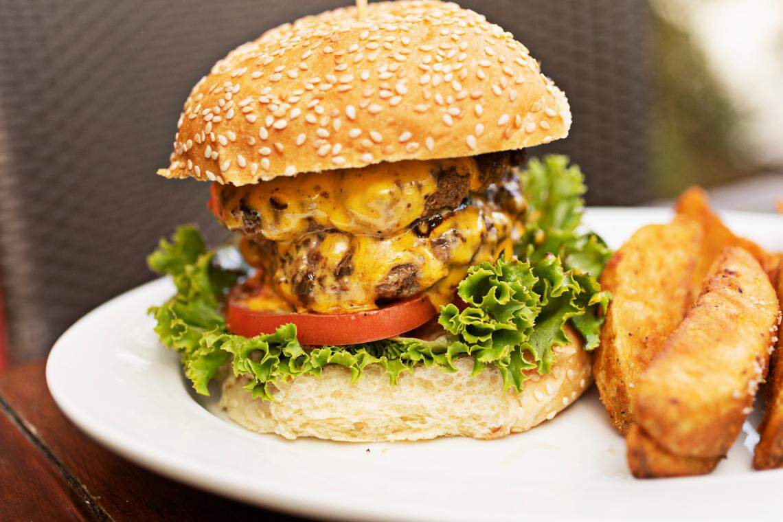 The Station Burger from The Station, a Raleigh restaurant set to close soon, is made with lettuce, onion, tomato and American cheese on a sesame seed bun with a side of potato wedges.