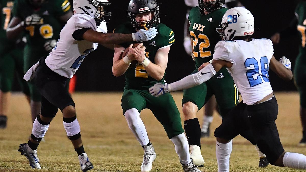 Apex quarterback Chase Kingmann (2) runs for yardage against Panther Creek’sMohamed Lemine (28) and Jeremiah Jones (21) during the second half. The Apex Cougars and the Panther Creek Catamounts met in a NCHSAA 4A 1st round football playoff game in Apex, NC on November 4, 2022.