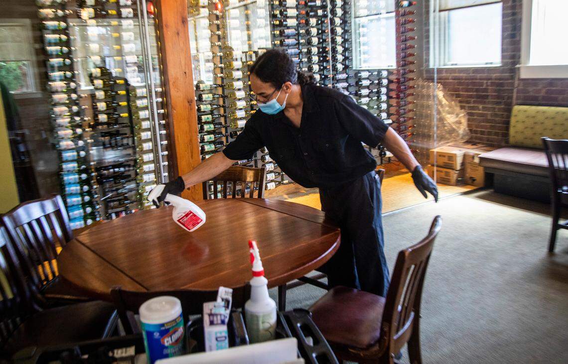 Jason Clark sanitizes a seating area during a mock service to help bring staff up to speed on new safety measures to prevent against the spread of coronavirus at The Pit in Raleigh Tuesday, May 26, 2020.The Pit owner Greg Hatem says he expects to open for dine-in on Wednesday afternoon, May 27, 2020.