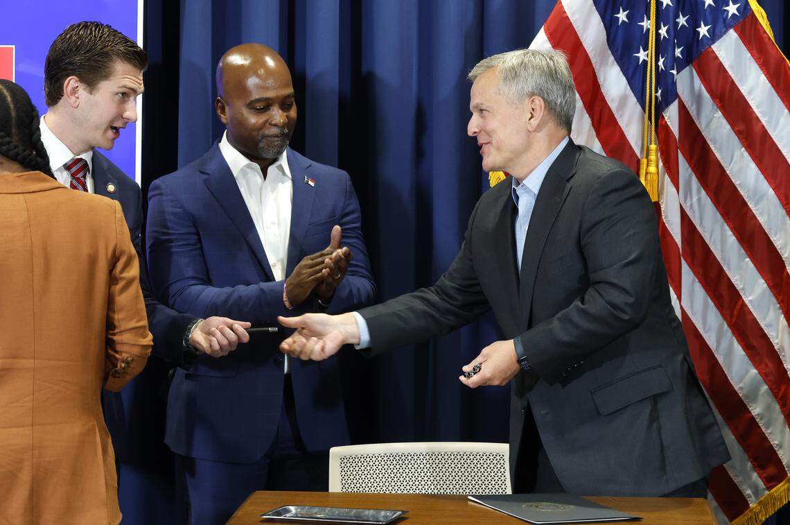 N.C. Governor Josh Stein gives Rep. Jake Johnson a pen after signing an executive order creating the Artificial Intelligence Leadership Council during a press conference in Raleigh, N.C., Tuesday, Sept. 2, 2025. Rep. Zack Hawkins stands in the center.