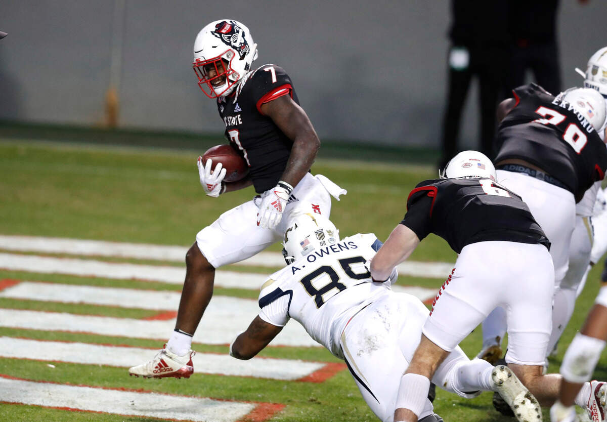 N.C. State running back Zonovan ‘Bam’ Knight (7) scores on a five-yard touchdown run during the first half of N.C. State’s game against Georgia Tech at Carter-Finley Stadium in Raleigh, N.C., Saturday, Dec. 5, 2020. Georgia Tech defensive lineman Antwan Owens (89) defends.