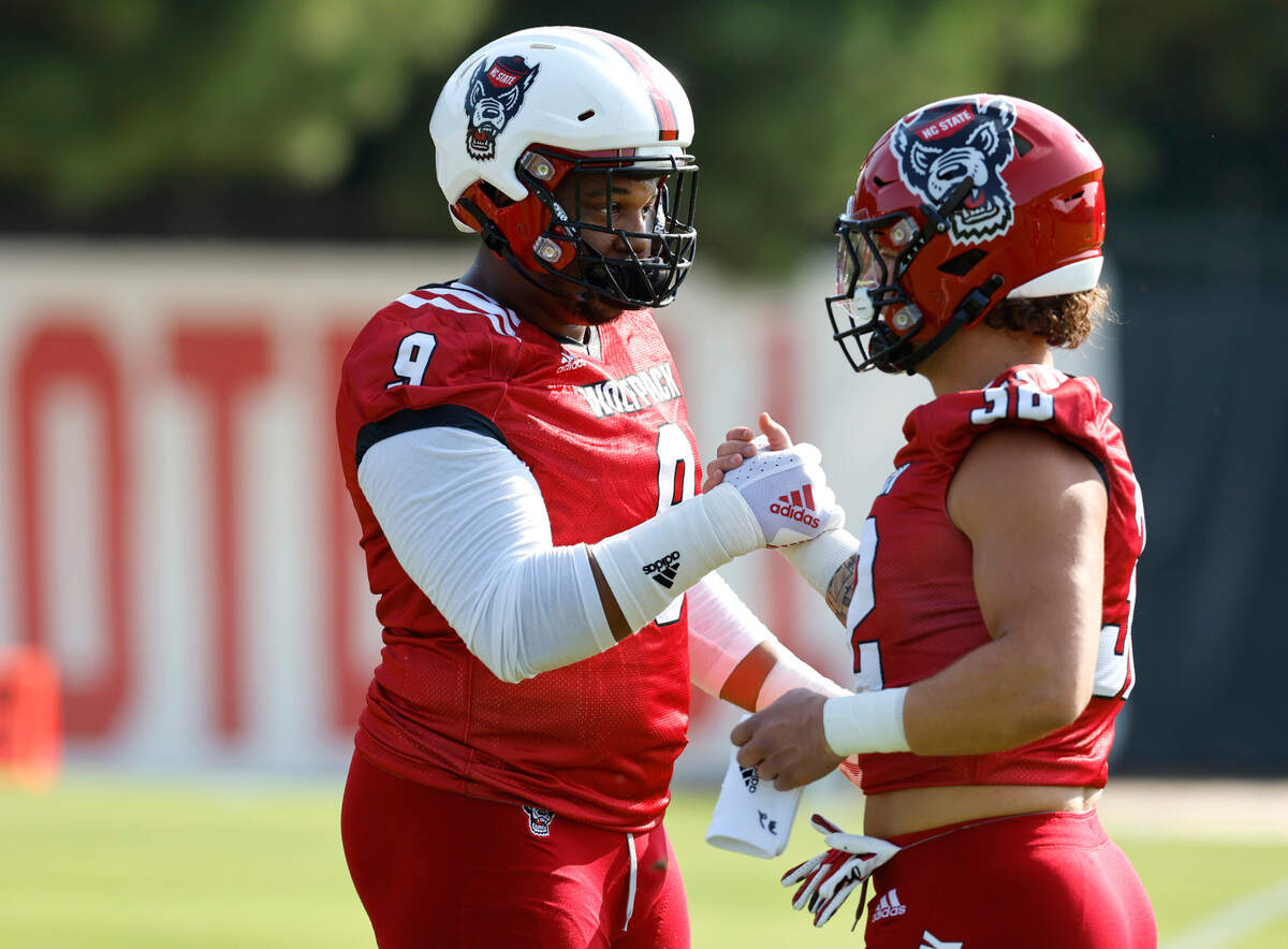 N.C. State defensive end Savion Jackson (9) greets Drake Thomas (32) at the start the Wolfpack’s first practice of fall camp in Raleigh, N.C., Wednesday, August 3, 2022.