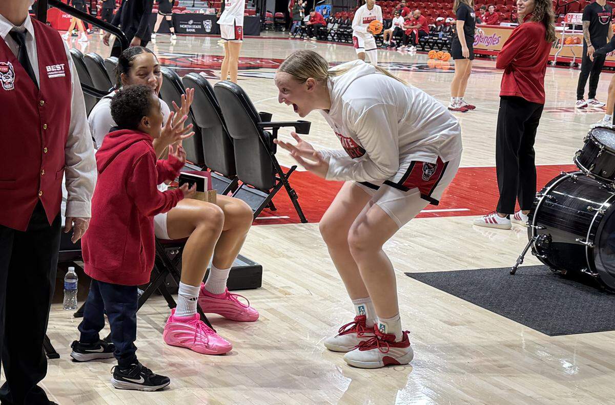 N.C. State guard forward Khamil Pierre and Maddie Cox play with fan Braylon Collins after a game at Reynolds Coliseum.
