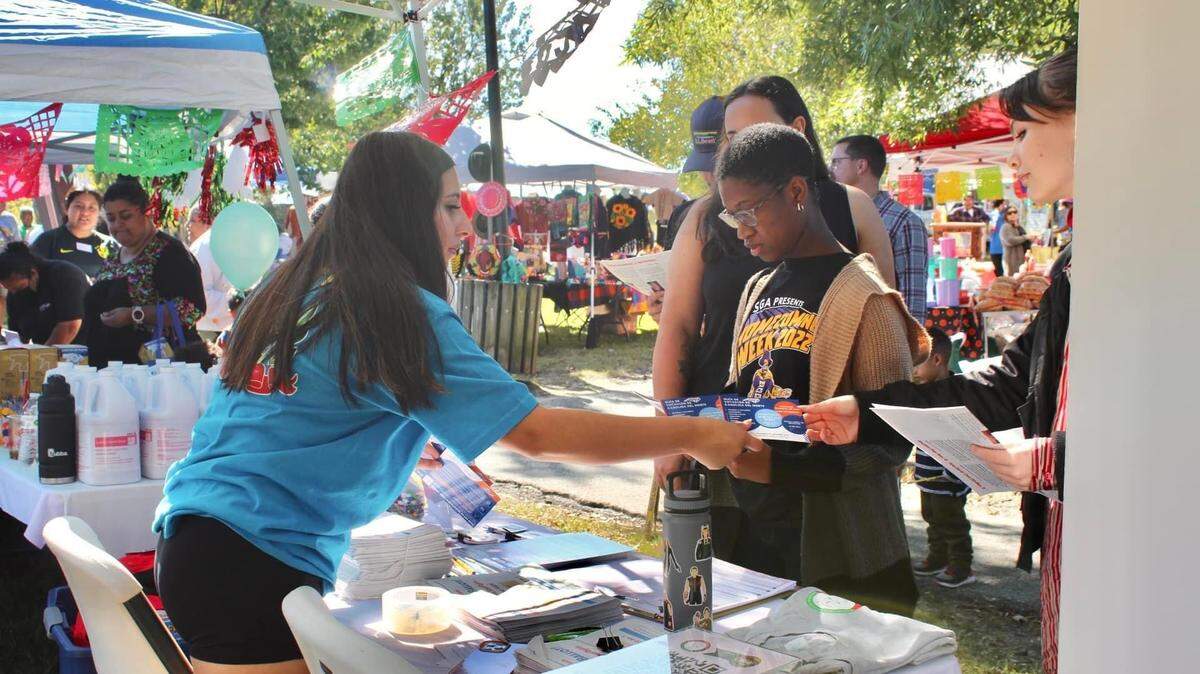 Fiorela Villegas, director of advocacy and civic engagement at the Association of Mexicans in North Carolina, Inc, hands people voter information during a registration event 